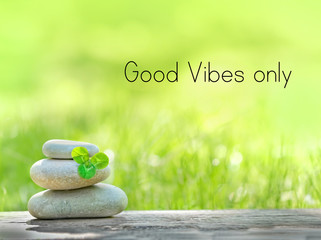 good vibes only - motivation quote. Stack of zen stones and Shamrock clover leaf on abstract nature background. Relax still life. zen pebble stones, spa wellness scene, soul calmness concept.