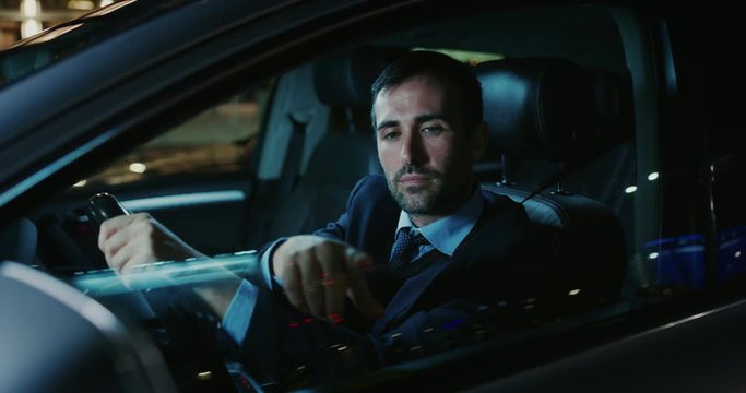 A handsome businessman is using an application of self pilot on a futuristic screen with augmented reality holograms  before a drive a car.