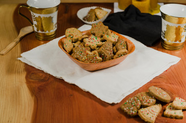 Plate and cups with delicious ginger cookies, cinnamon, chocolate, vanilla, on the table, closeup view Christmas