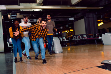Group of friends enjoying time together laughing and cheering while bowling at club.