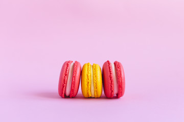 Three tasty french macarons on pink background.  Close-up.