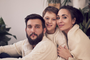 Happy family. Father, mother and boy. sitting together on the floor in knitted white sweaters