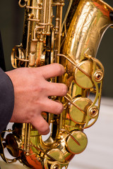hands pressing knobs while playing the saxophone