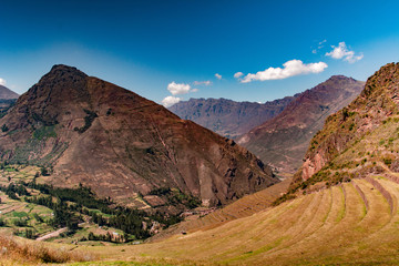 Snowy mountains with blue sky and white clouds, big hills with green pastures.