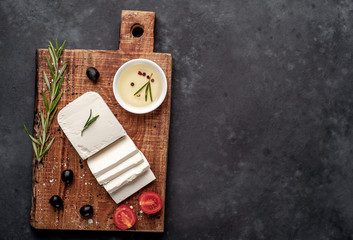 feta cheese, with rosemary, tomatoes, olives on a stone background. top view with copy space for your text