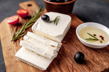 feta cheese, with rosemary, tomatoes, olives on a stone background