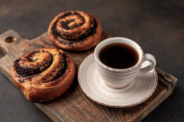 coffee and bun with poppy seeds on a stone background. breakfast concept