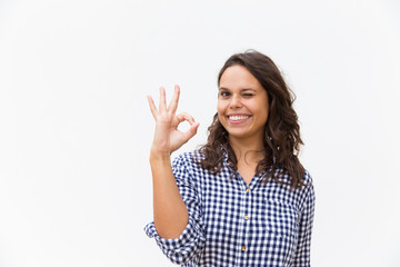 Joyful female customer making OK gesture, looking at camera, smiling. Young woman in casual checked shirt standing isolated over white background. Advertising concept