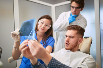 Patient with workpeople looking x-ray of teeth