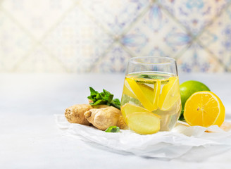 Ginger-lemon drink. Homemade Organic ginger in a glass with Lemon and mint on white table. Trendy detox healthy drink.