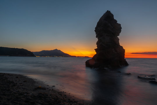 Isola di Procida, tramonto e faraglioni sul mare.