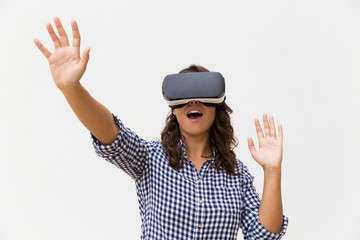 Excited student girl in VR goggles enjoying experience and shouting. Young woman in virtual reality headset standing isolated over white background. VR technology concept