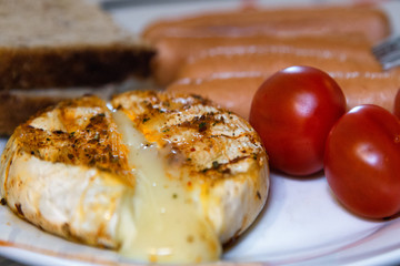 Grilled cheese hermelin close up on plate with red fresh tomatoes as breakfast concept. Selective focus.Blurred background. Over eating.