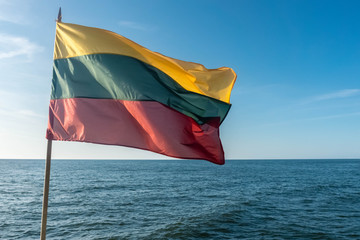 The flag of Lithuania flying in wind over Baltic sea on sky background