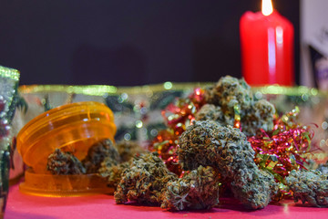 dried cannabis flowers and grinder with christmas decorations to celebrate the new year