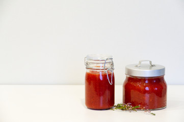 Jars of jam stand on a table on a light background. Near thyme