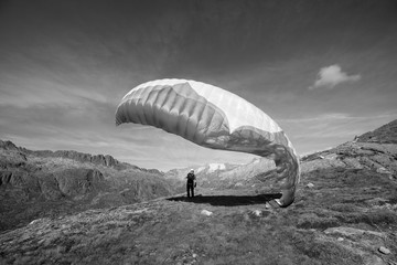 Young paraglider pilot uses his paraglider to play with the wind in the Swiss Alps, the so-called ground handling