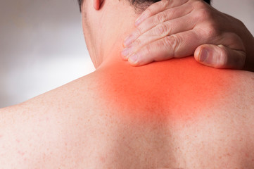 Man in his forties with cervical pain massage the base of the neck with his hand