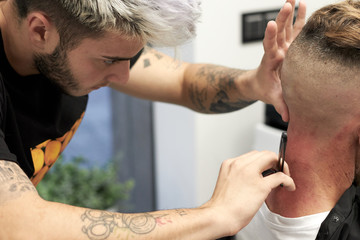 hairdresser cutting hair to man with traditional razor