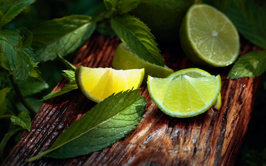 Lime slices and mint leaves on an old wooden background.