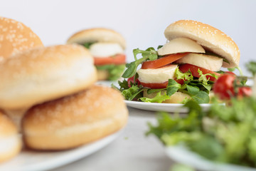 Sandwich with mozzarella, tomato and salad on the kitchen table.