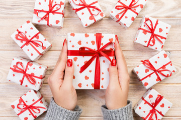 Woman hands give wrapped valentine or other holiday handmade present in paper with red ribbon....