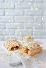 Almond flakes falling from above over caramel strudel