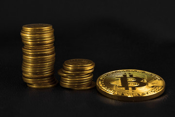 three piles of coins in ascending order, and a Golden coin bitcoin on black leather