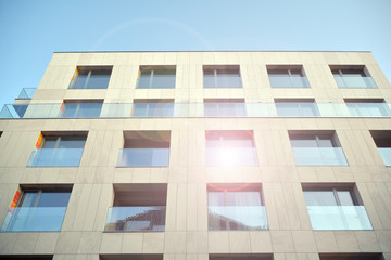 Modern apartment buildings on a sunny day with a blue sky. Facade of a modern apartment building. Glass surface with sunlight.