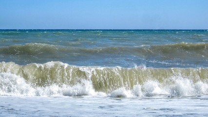 storm on the sea and big foamy waves roll over the sandy beach.