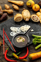Fototapeta na wymiar Asian lotus root began to be used in world kitchens. Slicies on old black stone deck on old wooden background, Miso Soup with Winter Vegetables