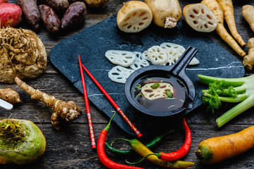 Asian lotus root began to be used in world kitchens. Slicies on old black stone deck on old wooden background, Miso Soup with Winter Vegetables