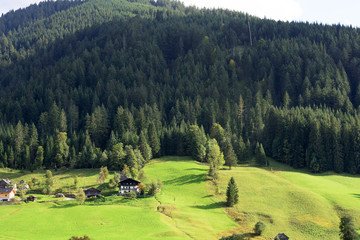 Fototapeta na wymiar Early morning in Austria. Traditional Austrian landscape: mountains, cozy houses and green lawns. Euro trip. Feeling of calm and stability.