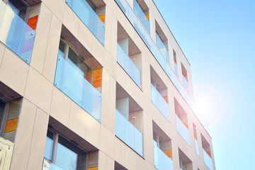 Modern apartment buildings on a sunny day with a blue sky. Facade of a modern apartment building. Glass surface with sunlight.