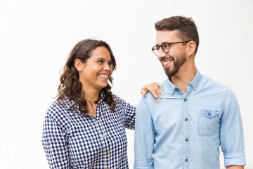 Happy satisfied couple chatting and laughing. Young woman in casual and man in glasses standing isolated over white background. Human communication concept
