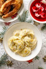 Christmas dumplings (pierogi) stuffed with forest mushrooms and cabbage on a white plate on a white...