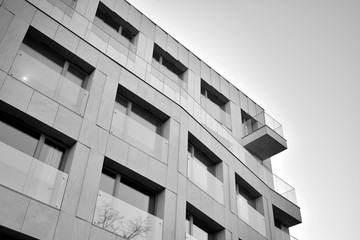 Detail of modern residential flat apartment building exterior. Fragment of new luxury house and home complex. Glass surface with sunlight. Black and white.