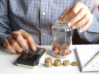 Man saving coin into a jar and accounting how money he has