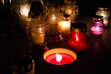 Monument and candles in the cemetery. All Saints Day in Poland. Candles in the cemetery. All candles in the dark.