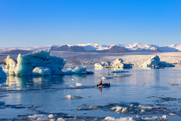 Jokulsarlon glacier lagoon in Iceland. Blue icebergs and tour boat on lake water. Northern nature landscape in Vatnajokull National Park