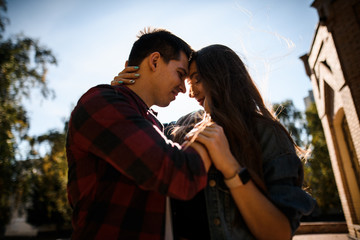 Happy man holding his woman on the face and looking into her eyes in the park