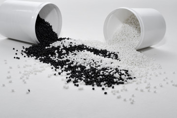 Glass with black and white termoplastic elastomer granules on a white background
