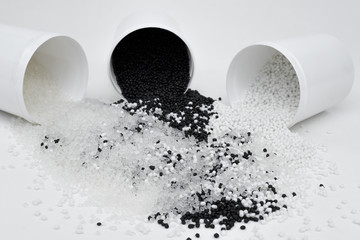 Glass with transparent, black and white termoplastic elastomer granules on a white background