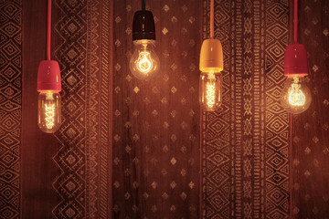 Decorative incandescent bulbs glow on the background of a wall with an ornament