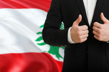 Lebanon businessman showing thumbs up behind country flag with copy space. Successful international...