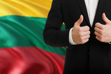 Lithuania businessman showing thumbs up behind country flag with copy space. Successful...