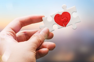 Puzzle pieces with painted red heart on background