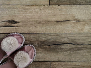 Feminine charming home slippers stand on a beautiful laminate floor with a natural oak texture. View from above.