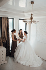 Naklejka premium Happy bride with her friends. Beautiful bride with her pretty bridesmaids. Morning of beautiful bride. Wedding day. Beautiful bride and bridesmaids posing in home on the wedding day. Best friends.