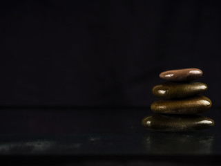 Spa Stones. black shiny zen stones with water drops over black background. Zen stones pile in raindrops, concept of calm, peace